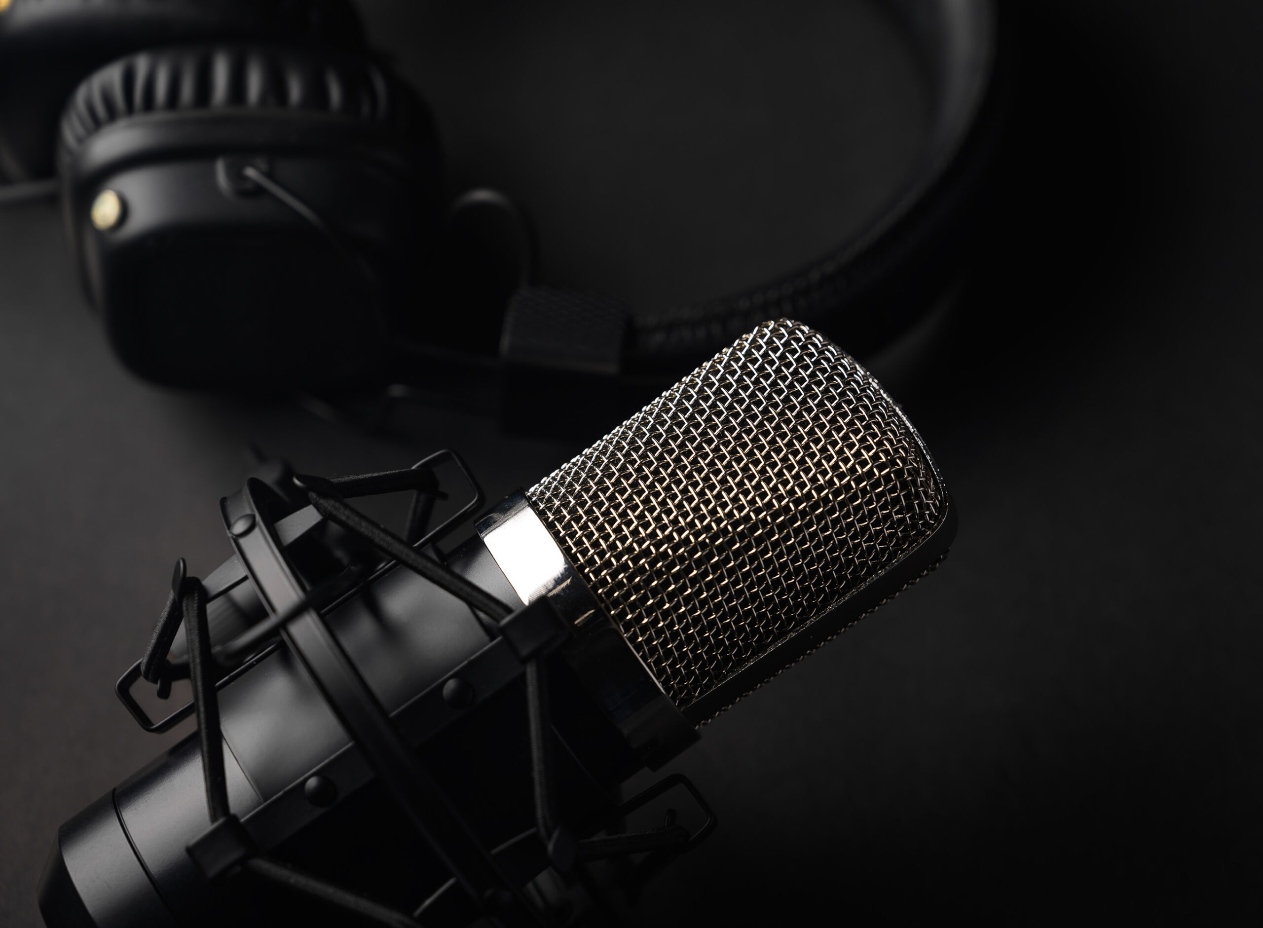 Studio black studio microphone with studio headphones on a black background. Banner. Radio, work with sound, podcasts.